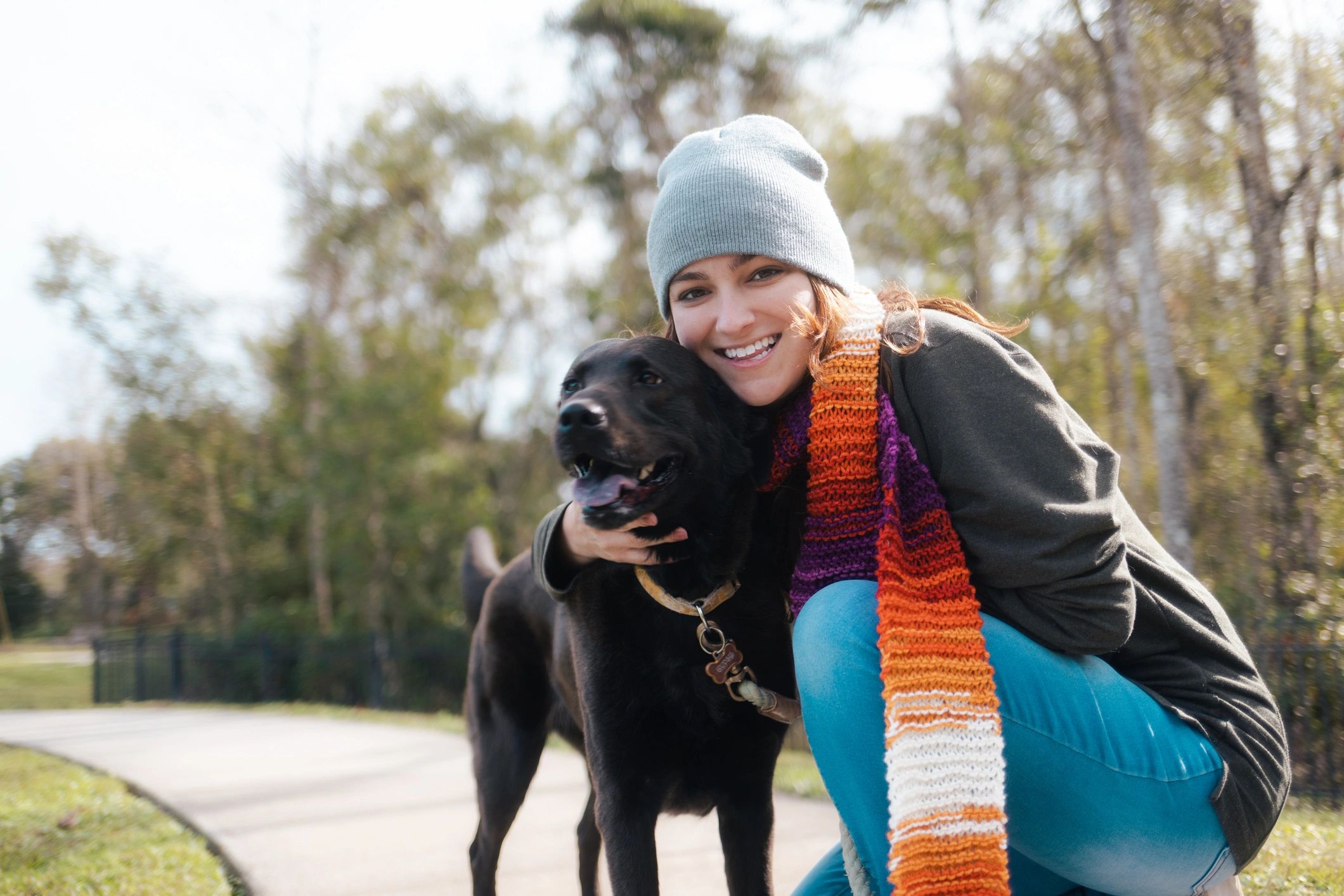 Dog walker sharing an affectionate moment with a Labrador during a walk